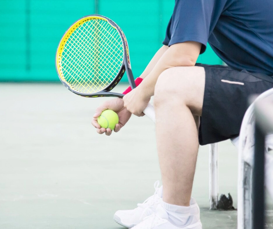 hombre con codo de tenista sentado en la cancha